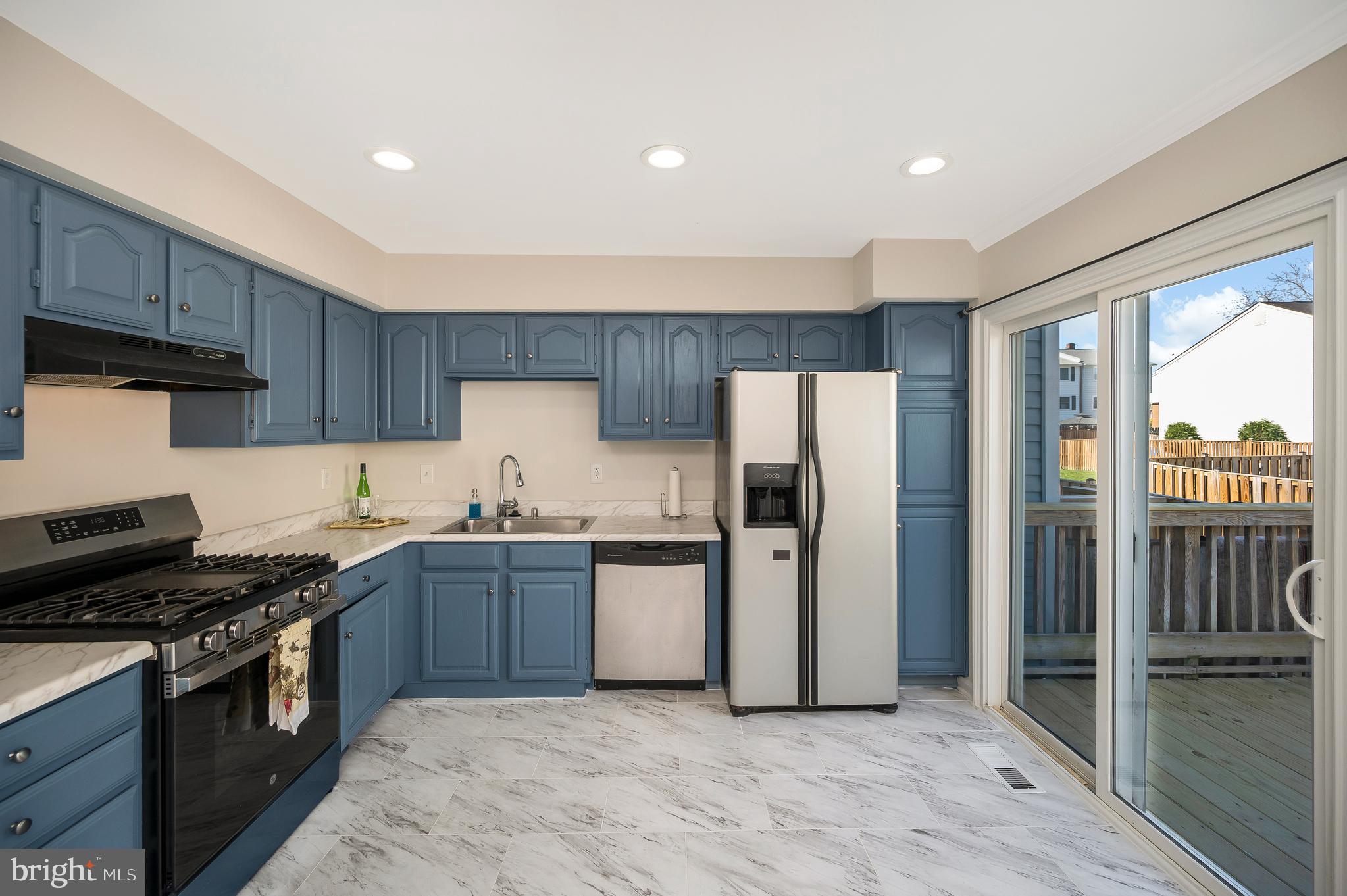 17950 Milroy Drive Dumfries, VA 22026 - Photo 11 of 42 a kitchen with stainless steel appliances granite countertop a stove top oven a refrigerator and a sink with wooden floor