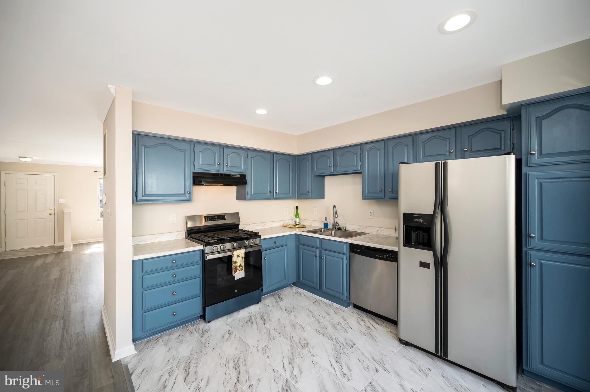 17950 Milroy Drive Dumfries, VA 22026 - Photo 12 of 42 a kitchen with stainless steel appliances granite countertop a stove top oven a refrigerator and white cabinets with wooden floor