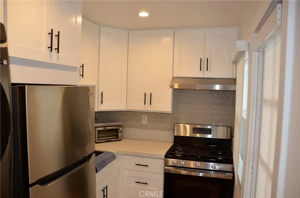 a kitchen with stainless steel appliances a refrigerator a stove and white cabinets
