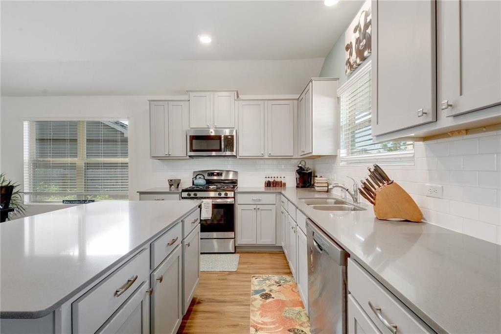 6813 Colorado Bluffs Road Austin, TX 78744 - Photo 4 of 20 Kitchen with stainless steel appliances, light wood-style flooring, a center island, recessed lighting, and tasteful backsplash