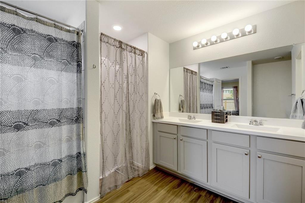 6813 Colorado Bluffs Road Austin, TX 78744 - Photo 10 of 20 Full bath with double vanity, light wood-style flooring, and a shower with curtain