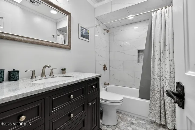 a bathroom with a granite countertop sink a toilet and shower
