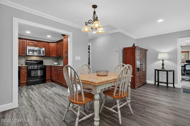 a dining room with wooden floor a chandelier a wooden table and chairs