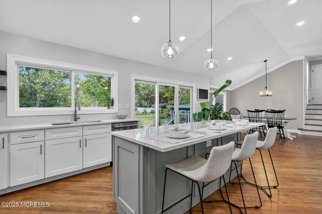 a kitchen with a stove a sink a counter top space and living room view