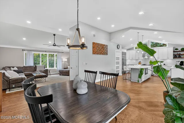 a view of a dining room and livingroom with furniture wooden floor a rug a flat screen tv and a chandelier