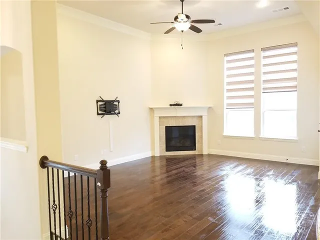 a view of a livingroom with a fireplace a ceiling fan and wooden floor