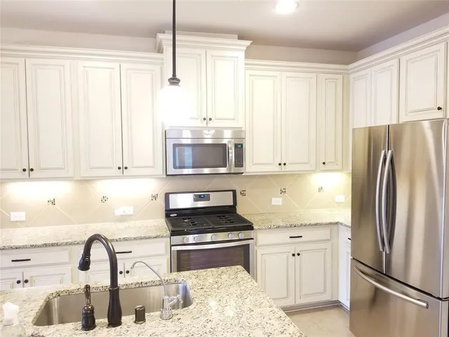 a kitchen with stainless steel appliances granite countertop a refrigerator sink and stove