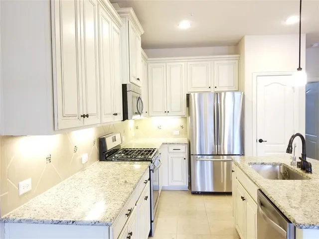 a kitchen with granite countertop a sink stainless steel appliances and cabinets