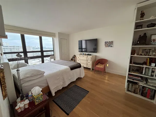 a bedroom with a bed a dresser and a flat screen tv