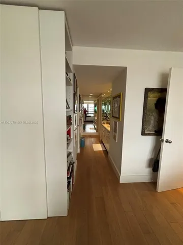 a view of a hallway with wooden floor and living room