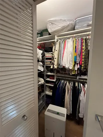 a view of walk in closet with clothes and shoes