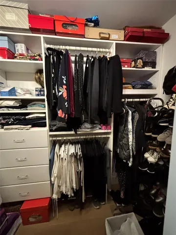 a view of walk in closet with clothes and shoes