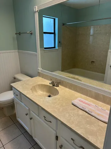 a bathroom with a granite countertop sink a toilet and shower
