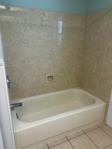 a white bath tub sitting next to a white sink and vanity