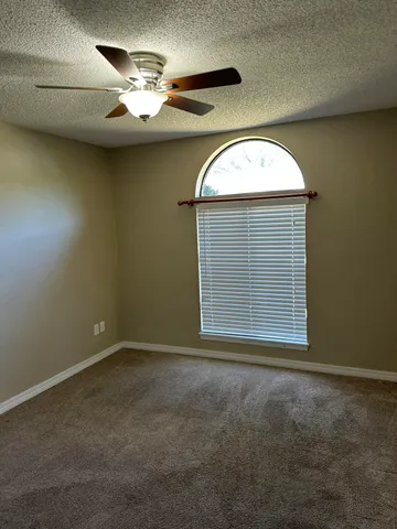 an empty room with a chandelier fan and windows
