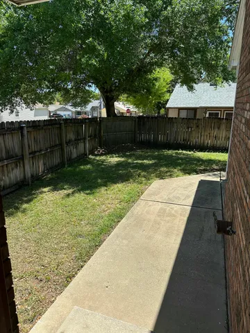 a view of backyard with wooden fence and a large tree