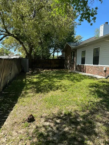 a backyard of a house with table and chairs potted plants and large tree