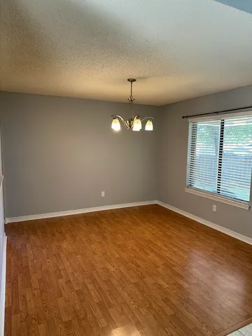 an empty room with chandelier fan and windows