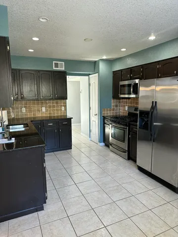 a kitchen with granite countertop a refrigerator and a stove top oven