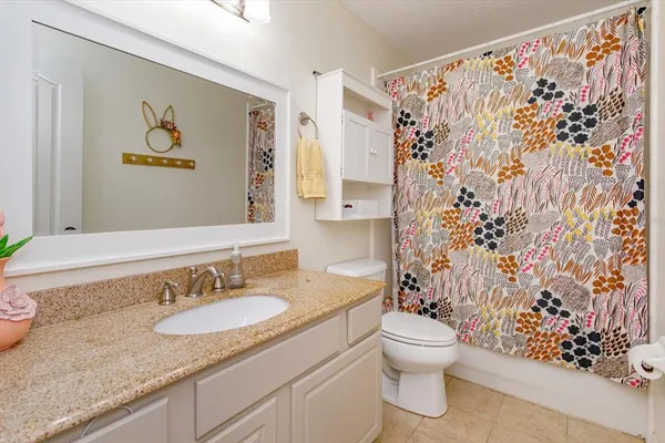 a bathroom with a granite countertop sink toilet and a mirror