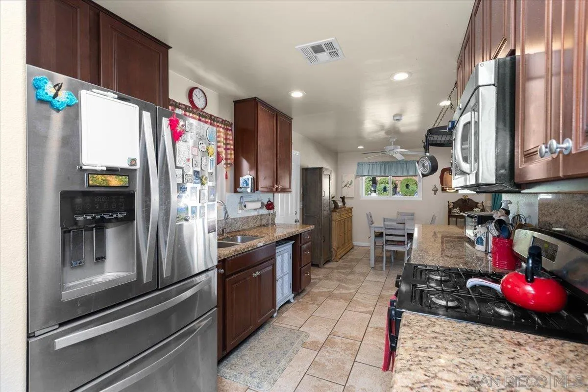 9254 Shadow Hill Road Santee, CA 92071 - Photo 13 of 34 a kitchen with stainless steel appliances granite countertop a sink refrigerator and cabinets