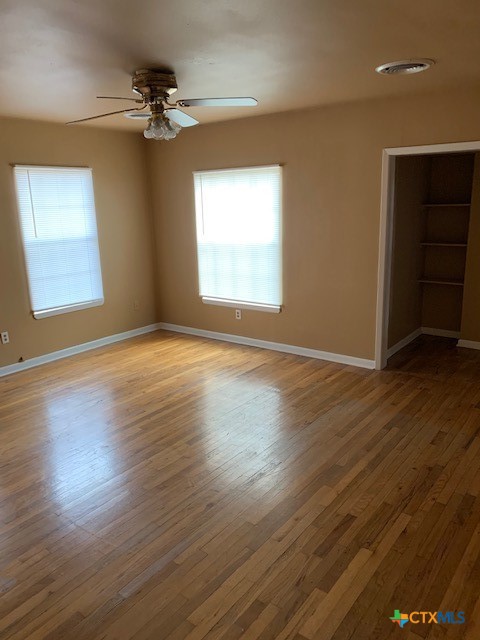 1205 Florence Road Killeen, TX 76541 - Photo 4 of 15 an empty room with wooden floor chandelier fan and windows