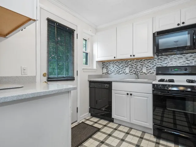 a kitchen with granite countertop a stove a sink and a microwave