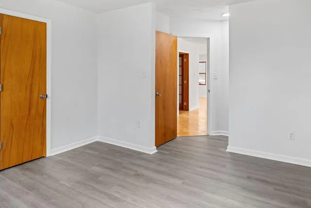 a view of an empty room with wooden floor and closet