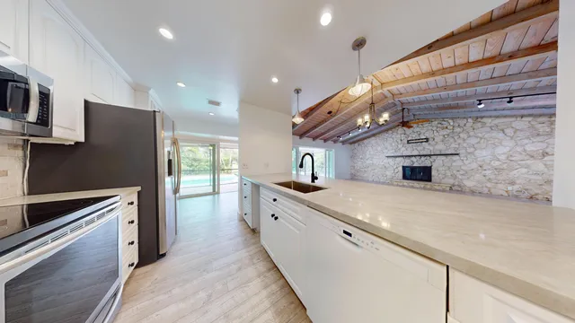 a large kitchen with stainless steel appliances kitchen island a large counter top a stove and a refrigerator