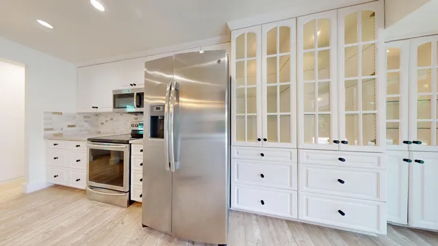 a kitchen with cabinets stainless steel appliances and a window