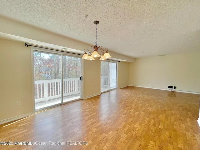 a view of a room with wooden floor chandelier and windows