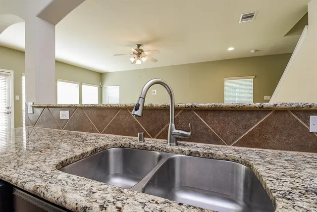 a view of a sink a faucet a fireplace and cabinets