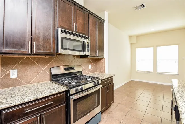 a kitchen with granite countertop a stove a sink and a microwave