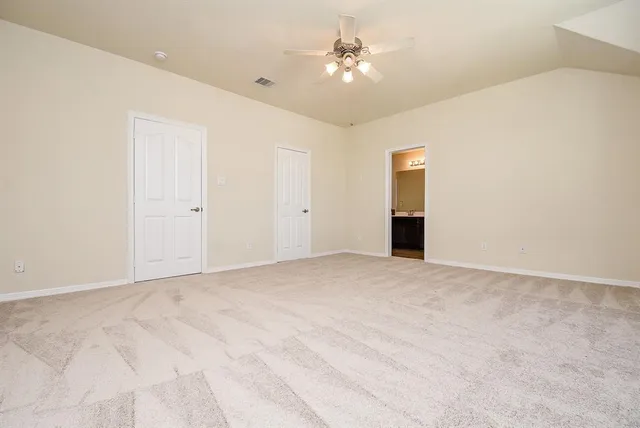 a view of an empty room with chandelier fan