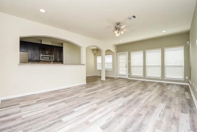 a view of an empty room with a window and wooden floor