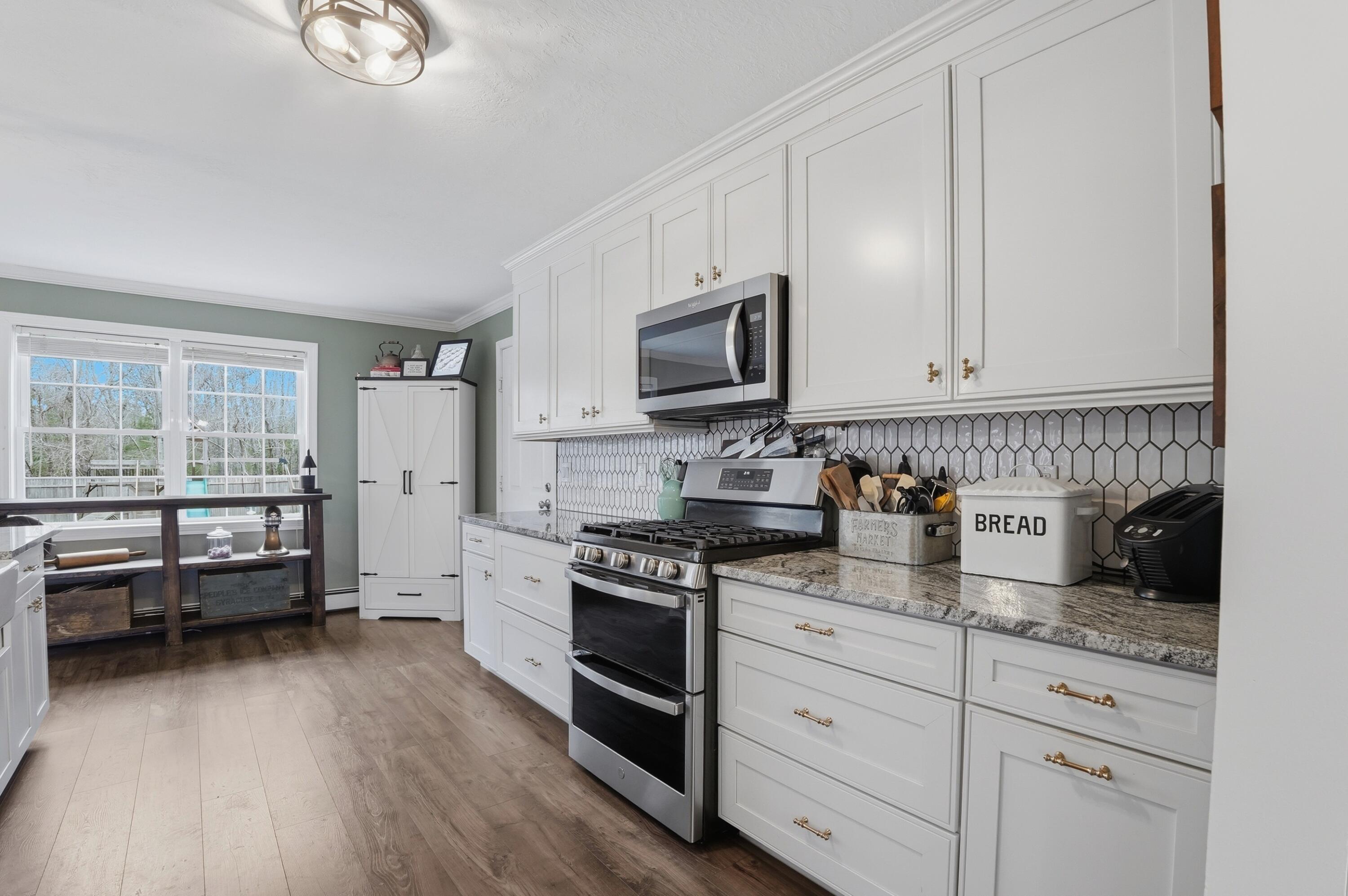 3 Dover Lane Buzzards Bay, MA 02532 - Photo 8 of 51 a kitchen with granite countertop a stove a sink and white cabinets with wooden floor