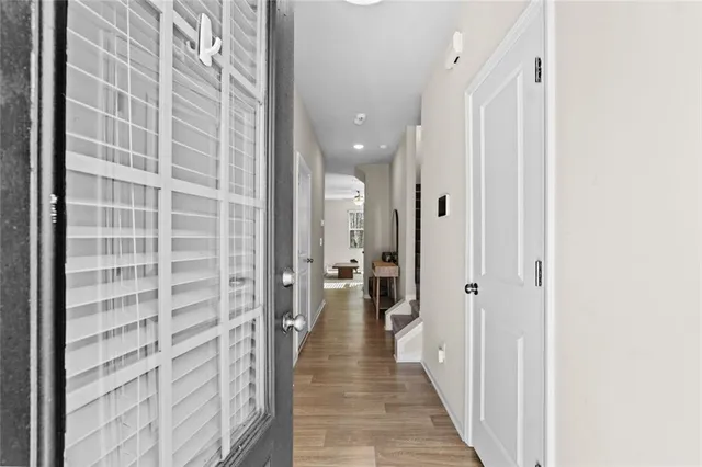 a view of a hallway with wooden floor and a bathroom