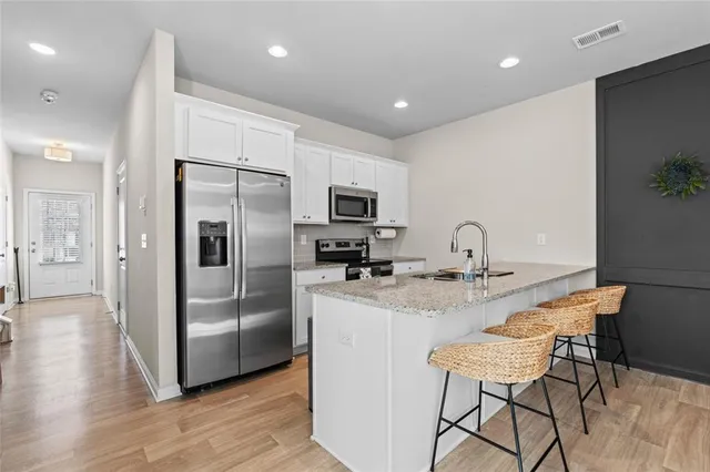 a kitchen with stainless steel appliances granite countertop a refrigerator a stove a sink a dining table and chairs