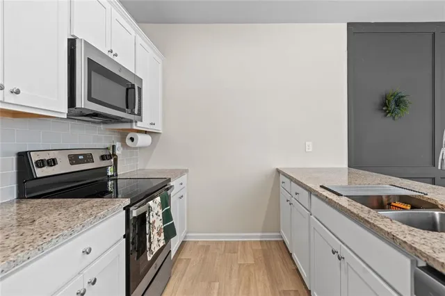 a kitchen with granite countertop a sink and a stove top oven