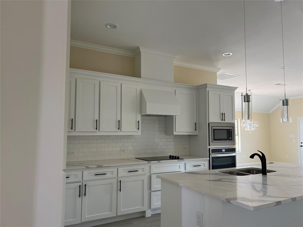 8008 County Road 1058 Rice, TX 75155 - Photo 9 of 25 Gourmet kitchen featuring white shaker cabinetry, an island with dual sinks, and white quartz countertops with gray veining