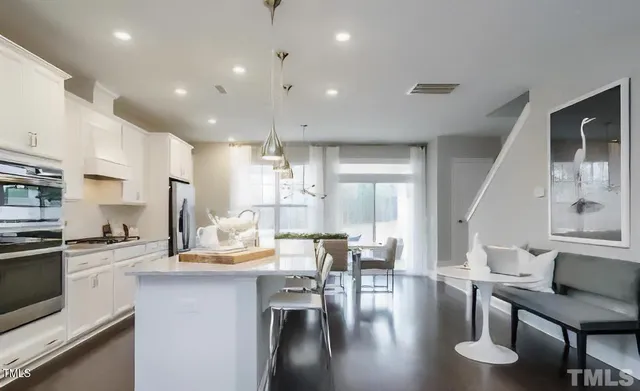 a large kitchen with kitchen island a large island a sink a stove a dining table and chairs