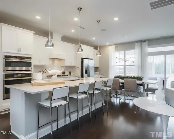 a kitchen with stainless steel appliances kitchen island granite countertop a kitchen island and chairs in it