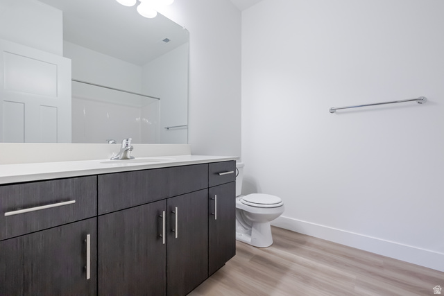 Contemporary vanity with dark wood-finish cabinetry, white countertop, and integrated sink