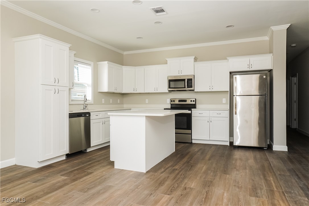 12315 Tangier Street North Port, FL 34287 - Photo 5 of 16 a kitchen with a refrigerator a stove top oven a sink and white cabinets with wooden floor