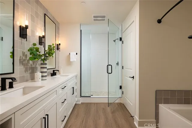 a bathroom with a double vanity sink a large mirror a bathtub and shower