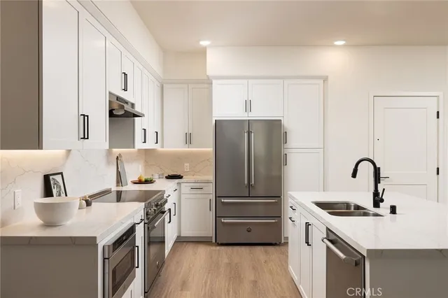 a kitchen with a sink a refrigerator and a stove top oven with wooden floor