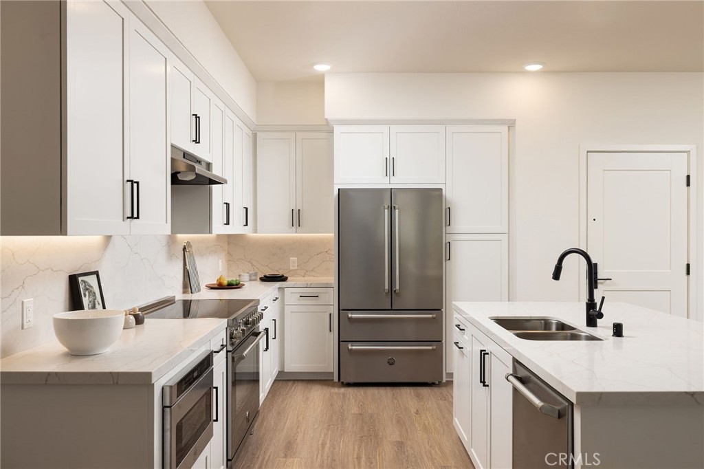 414 Main Street, Unit 310 Huntington Beach, CA 92648 - Photo 6 of 25 a kitchen with a sink a refrigerator and a stove top oven with wooden floor