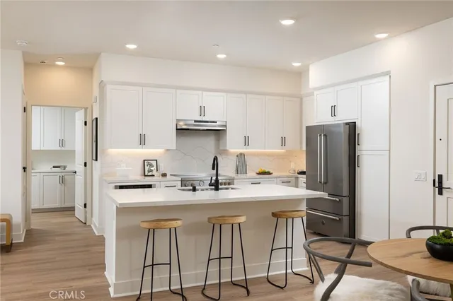 a kitchen with stainless steel appliances granite countertop a sink a stove a refrigerator and cabinets