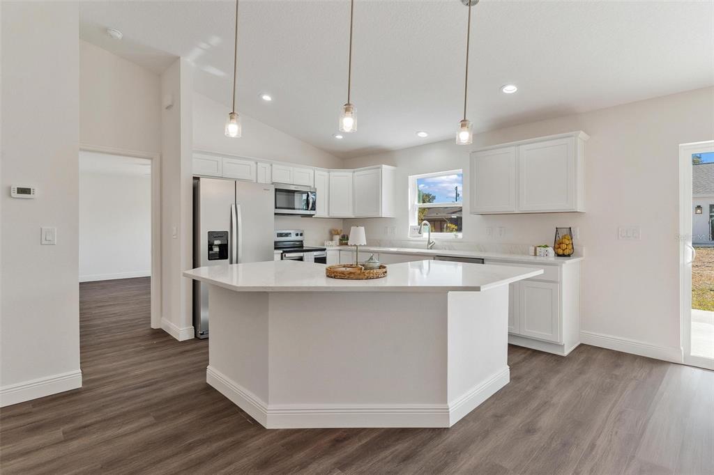 2011 Edgewood Avenue Leesburg, FL 34748 - Photo 14 of 44 a kitchen with stainless steel appliances a refrigerator a sink dishwasher a stove and white cabinets with wooden floor