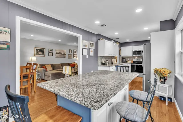 a kitchen with stainless steel appliances granite countertop a dining table chairs and refrigerator